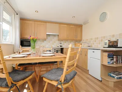 a kitchen with a wooden table and chairs in a kitchen at Little Trebah in St Merryn