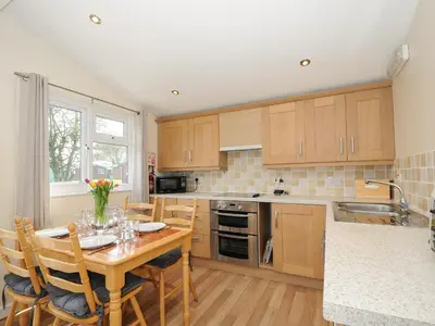 a kitchen with a wooden table with chairs and a dining room at Little Trebah in St Merryn
