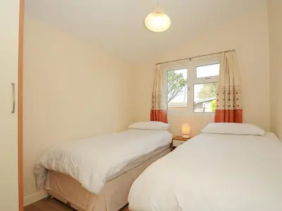 two beds in a small room with a window at Little Trebah in St Merryn