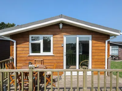 a wooden cabin with a table and chairs on a deck at Little Trebah in St Merryn