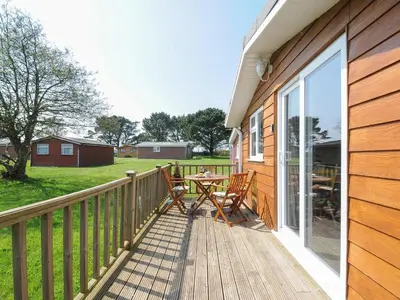 a wooden deck with a table and chairs on it at Little Trebah in St Merryn
