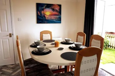 a dining room table with chairs and a table with cups and plates at Parc Trethias in St Merryn