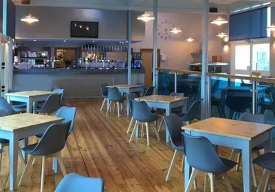 a restaurant with tables and chairs and a bar at Parc Trethias in St Merryn