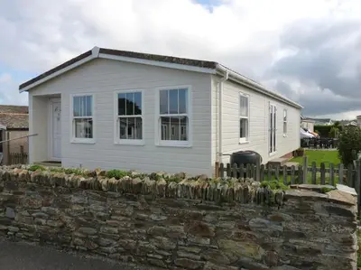 a white house with a stone fence in front of it at Parc Trethias in St Merryn
