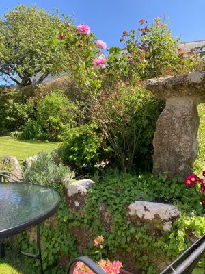 a garden with a table and flowers and a bird bath at Spacious flat St Ives former farmhouse, parking in St Ives