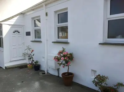a white house with two potted plants and a door at Spacious flat St Ives former farmhouse, parking in St Ives