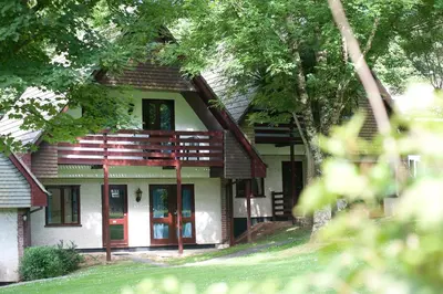 a house with red doors and trees at Tolroy Manor Holiday Park in Hayle