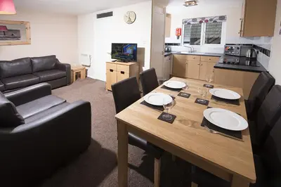a living room with a dining table and a kitchen at Tolroy Manor Holiday Park in Hayle