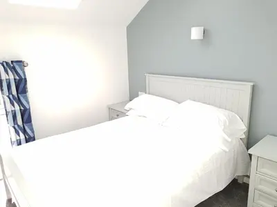 a white bedroom with a bed and a desk at Tolroy Manor Holiday Park in Hayle