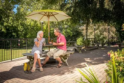a man and woman sitting at a picnic table under an umbrella at Tolroy Manor Holiday Park in Hayle