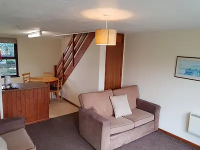 a living room with a chair and a staircase at Tolroy Manor Holiday Park in Hayle
