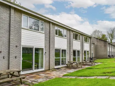 a building with large windows and benches in the yard at Fifty Six in Saint Columb Major