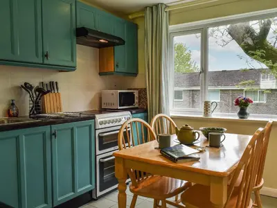 a kitchen with green cabinets and a table with chairs at Fifty Six in Saint Columb Major