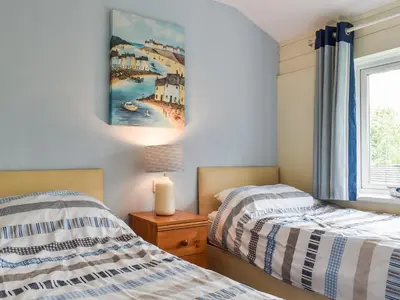 two beds in a bedroom with a painting on the wall at Fifty Six in Saint Columb Major
