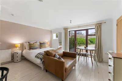 a bedroom with a bed and a chair and a table at The Rosevine in Porthscatho
