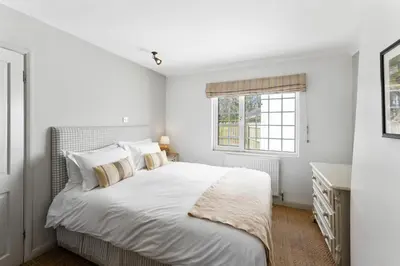 a white bedroom with a bed and a window at The Rosevine in Porthscatho
