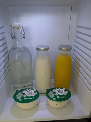 a refrigerator with two bottles of milk and two drinks at Private Double Room and Ensuite in Historic Cornish Cottage in Helston