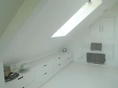an attic kitchen with white cabinets and a skylight at Private Double Room and Ensuite in Historic Cornish Cottage in Helston