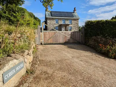 a gate to a stone house with a solar roof at Private Double Room and Ensuite in Historic Cornish Cottage in Helston