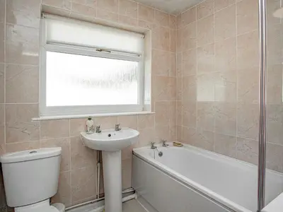 a bathroom with a sink and a toilet and a window at Squirrels Leap in Saint Cleer