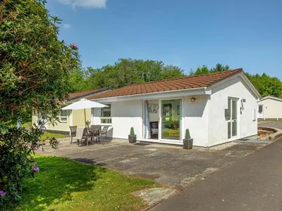 a white house with a patio and an umbrella at Squirrels Leap in Saint Cleer