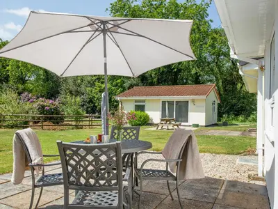 a table and chairs with an umbrella on a patio at Squirrels Leap in Saint Cleer