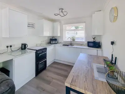 a kitchen with white cabinets and a wooden table at Squirrels Leap in Saint Cleer
