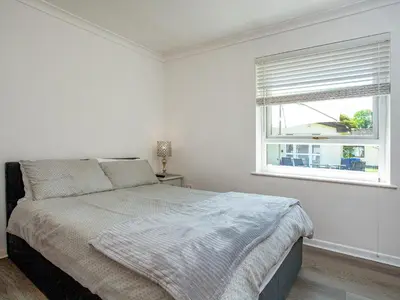 a white bedroom with a bed and a window at Squirrels Leap in Saint Cleer