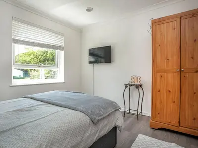 a bedroom with a bed and a wooden cabinet at Squirrels Leap in Saint Cleer