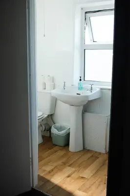 a white bathroom with a sink and a window at Elemental Surf Lodge in Newquay