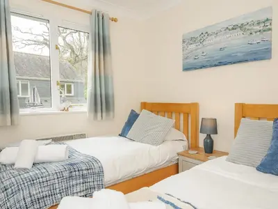a bedroom with two beds and a window at Woodmans Cottage in Falmouth