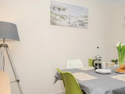 a dining room with a table and green chairs at Woodmans Cottage in Falmouth