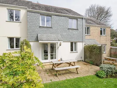 a house with a picnic table in front of it at Woodmans Cottage in Falmouth