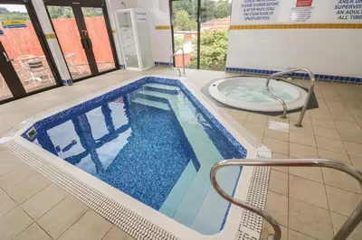 a large swimming pool with a tub in a building at Woodmans Cottage in Falmouth