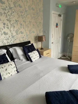 a bedroom with a large bed with blue and white pillows at No 52 bed and breakfast in Helston