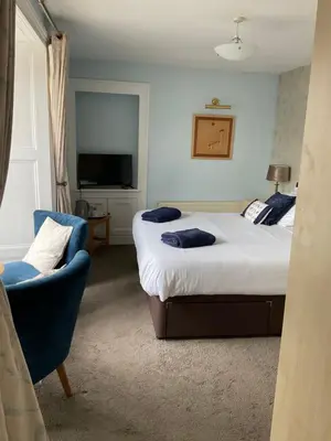 a bedroom with two beds and a chair and a television at No 52 bed and breakfast in Helston
