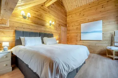 a bedroom with a large bed in a wooden wall at 3 Bed in Wadebridge oc-p00104 in Little Petherick