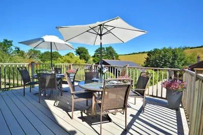 a deck with a table and chairs and an umbrella at 3 Bed in Wadebridge oc-p00104 in Little Petherick