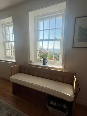 a bench in a room with two windows at 2a Coastguard Cottages in Gorran Haven
