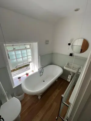 a white bath tub in a bathroom with a window at 2a Coastguard Cottages in Gorran Haven