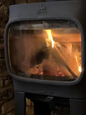 a person is cooking food in an oven at 2a Coastguard Cottages in Gorran Haven