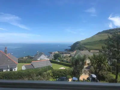 a view of a house with the ocean in the background at 2a Coastguard Cottages in Gorran Haven