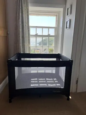 a black crib in a room with a window at 2a Coastguard Cottages in Gorran Haven