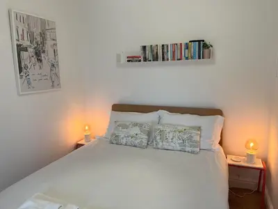a bedroom with a white bed with two lamps and books at 2a Coastguard Cottages in Gorran Haven
