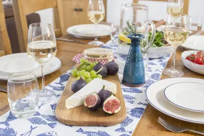 a wooden table with plates and glasses of wine at 3 Bed in Porthleven oc-12bayv in Porthleven