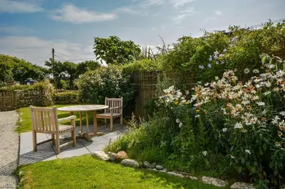 a table and chairs in a garden with flowers at 1 Bed in Rinsey oc-1chapl in Praa Sands