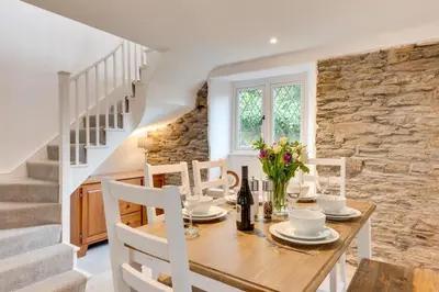 a dining room with a table and chairs and a stone wall at 3 Bed in Fowey oc-1cobbs in Fowey
