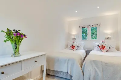 a white bedroom with two beds and a vase of flowers at 3 Bed in Fowey oc-1cobbs in Fowey