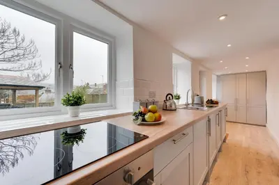 a kitchen with white cabinets and a large window at 3 Bed in Fowey oc-1cobbs in Fowey