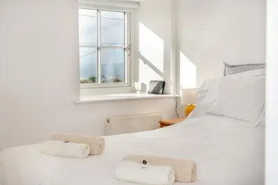 a white bed with two towels on it with a window at 2 Bed in Rinsey oc-2chapl in Praa Sands